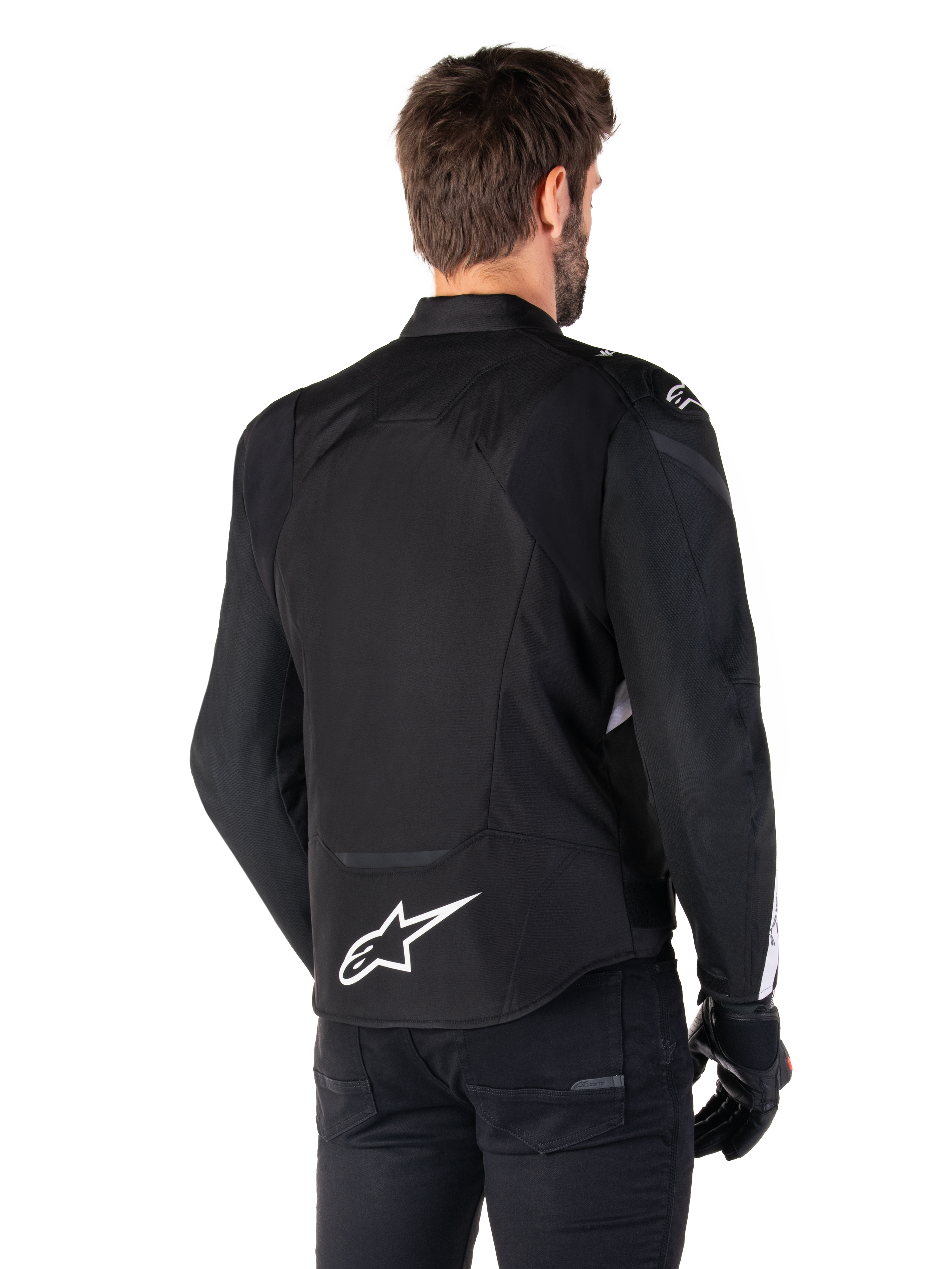 Alpinestars T-Jaws V4 Wasserdichte Jacke, Schwarz und Weiß, Rückansicht, Textil-Sportmotorradjacke mit weißem Logo am unteren Rücken, getragen mit schwarzen Handschuhen und Hosen, mit einer überarbeiteten sportlichen Silhouette