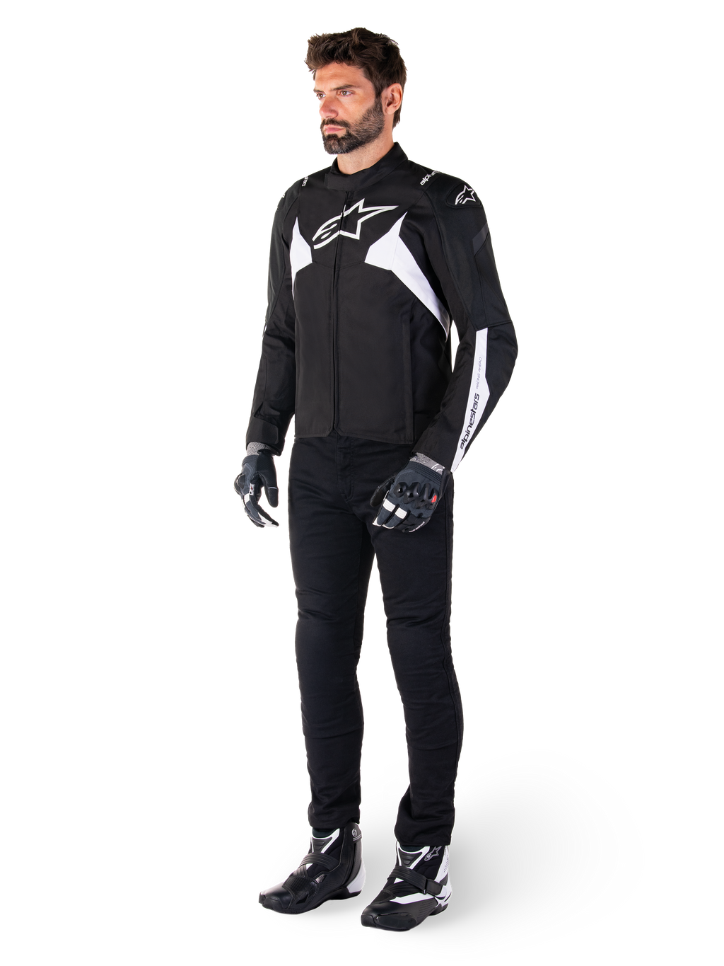 Männliches Model trägt die Alpinestars T-Jaws V4 Waterproof Jacke in Schwarz und Weiß, sportliche Textiljacke mit weißem Stern-Logo und Ärmelakzenten, kombiniert mit schwarzer Motorradhose, Handschuhen und Stiefeln für einen kompletten Road-Riding-Look.