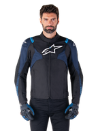 Alpinestars T-Jaws V4 Wasserdichte Jacke, Motorradjacke, Schwarz und Dunkelblau mit Blithe Blue Akzenten, weißes Logo auf der Brust, blauer Schriftzug auf den Schultern, getragen mit passenden Handschuhen, wasserdichte Textil-Fahrausrüstung