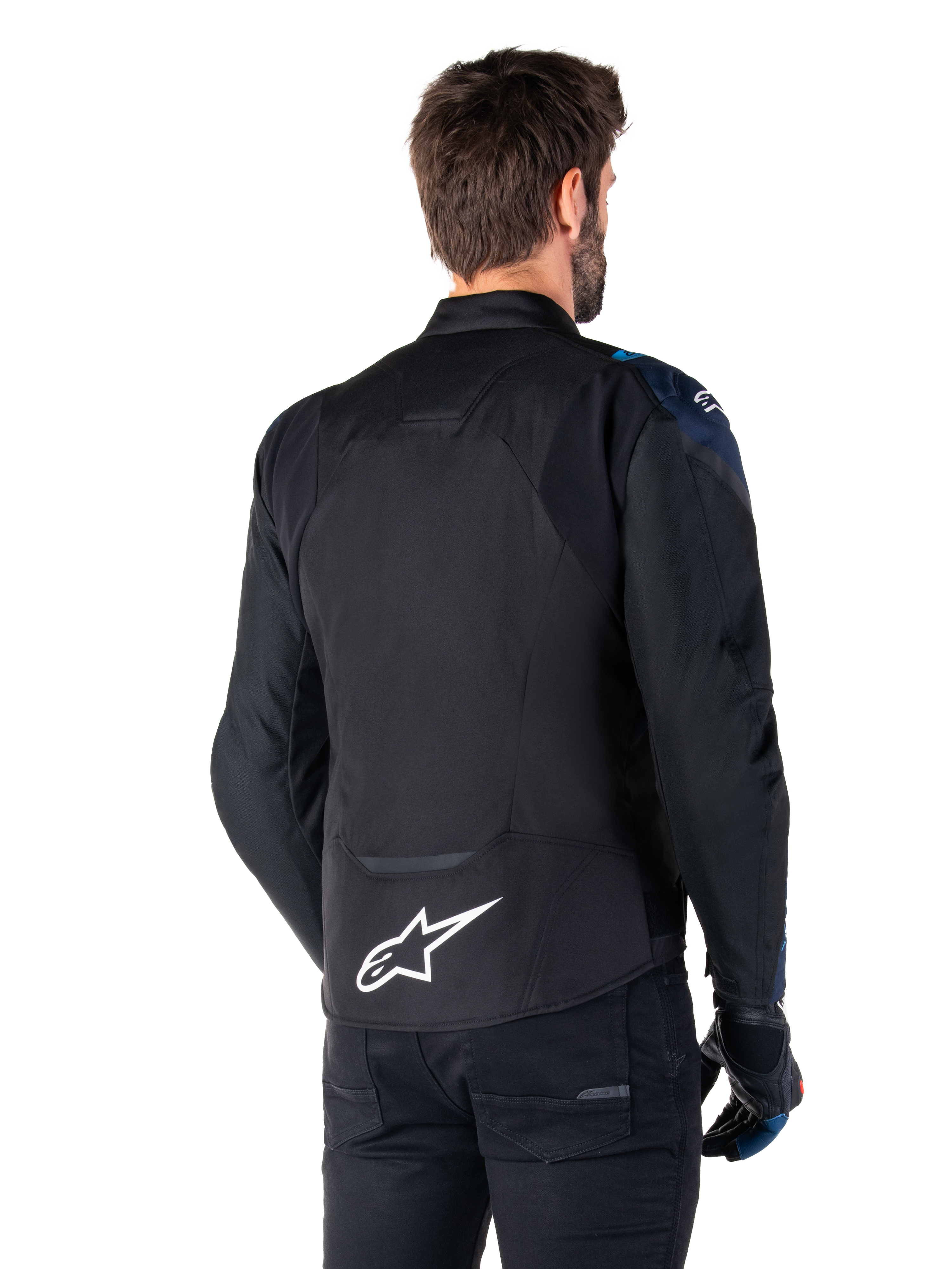 Alpinestars T-Jaws V4 Wasserdichte Jacke, Rückansicht, Schwarz mit dunkelblauen und hellblauen Details, weißes Stern-Logo am unteren Rücken, sportliche Silhouette, getragen mit schwarzer Hose und Motorradhandschuhen