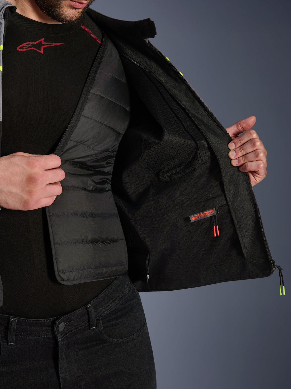 Alpinestars T-Jaws V4 Wasserdichte Jacke, Innenansicht, zeigt das herausnehmbare schwarze gesteppte Thermofutter und ein rot beschriftetes wasserdichtes Innenfach, Mesh-Futter, hochwertige Motorrad-Schutzausrüstung.