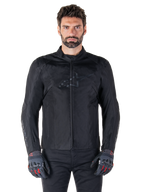 Alpinestars T-SPS V2 Waterproof Jacket, schwarze Motorrad-Textiljacke, getragen von einem Fahrer mit schwarz-roten Handschuhen, hoher Kragen, Reißverschluss vorne, dezentes Brustlogo, wasserdichter Schutz für sportliches und urbanes Fahren