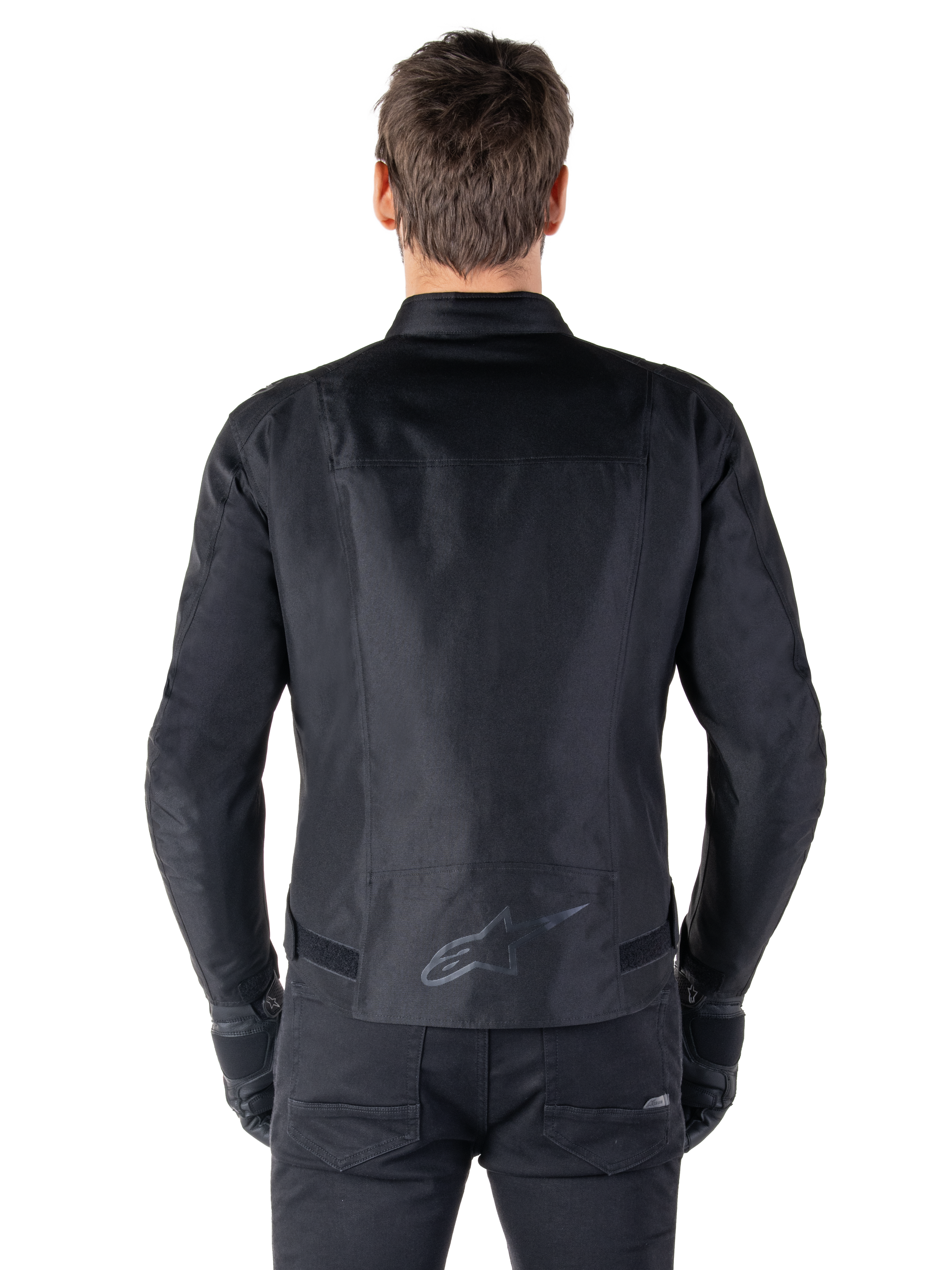 Alpinestars T-SPS V2 Wasserdichte Jacke, Schwarz, Rückansicht zeigt die sportliche Silhouette, reflektierendes Alpinestars-Logo am unteren Rücken und verlängerte Rückenpartie für zusätzliche Abdeckung beim Fahren.