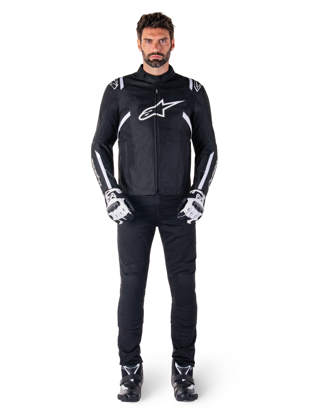 Alpinestars T-SPS V2 wasserdichte Jacke, Schwarz und Weiß, getragen von männlichem Model mit schwarzer Hose und passenden Handschuhen, weißes Alpinestars-Logo auf der Brust und Akzente an den Ärmeln, sportliche Silhouette für Allwetter-Motorradfahrten