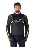 Alpinestars T-SPS V2 Waterproof Jacke, Motorradjacke, Schwarz mit weißen und neongelben Akzenten, getragen von einem Model mit schwarzen Handschuhen, mit weißem Stern-Logo auf der Brust und neongelben Streifen an Ärmeln und Schultern, sportliche Textilausrüstung für jedes Wetter