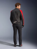 Alpinestars T-SPS V2 Wasserdichte Jacke, Schwarz Rot Rot Fluo, Rückansicht an einem männlichen Modell, weißes Alpinestars-Logo am unteren Rücken, getragen mit schwarzer Motorradhose und Handschuhen, sportliche wasserdichte Textil-Motorradjacke