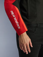 Alpinestars T-SPS V2 Wasserdichte Jacke, Motorradjacke, Schwarz und Rot, Nahaufnahme des Ärmels mit einem weißen vertikalen Markenlogo auf einem roten Einsatz, strapazierfähige Textilkonstruktion mit sportlich inspiriertem Design.