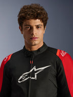 Männliches Model in der Alpinestars T-SPS V2 Waterproof Jacke, Schwarz mit roten Akzenten und weißem Logo, Nahaufnahme Porträtansicht, sportliche Textil-Motorradjacke
