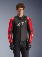 Alpinestars T-SPS V2 Waterproof Jacke, Textil-Motorradjacke, Schwarz und Rot, getragen von einem männlichen Modell mit passenden schwarzen Handschuhen, mit großem weißen Logo auf der Brust und weißem Branding auf roten Ärmeln, sportliche Silhouette für Straßenfahrten bei jedem Wetter