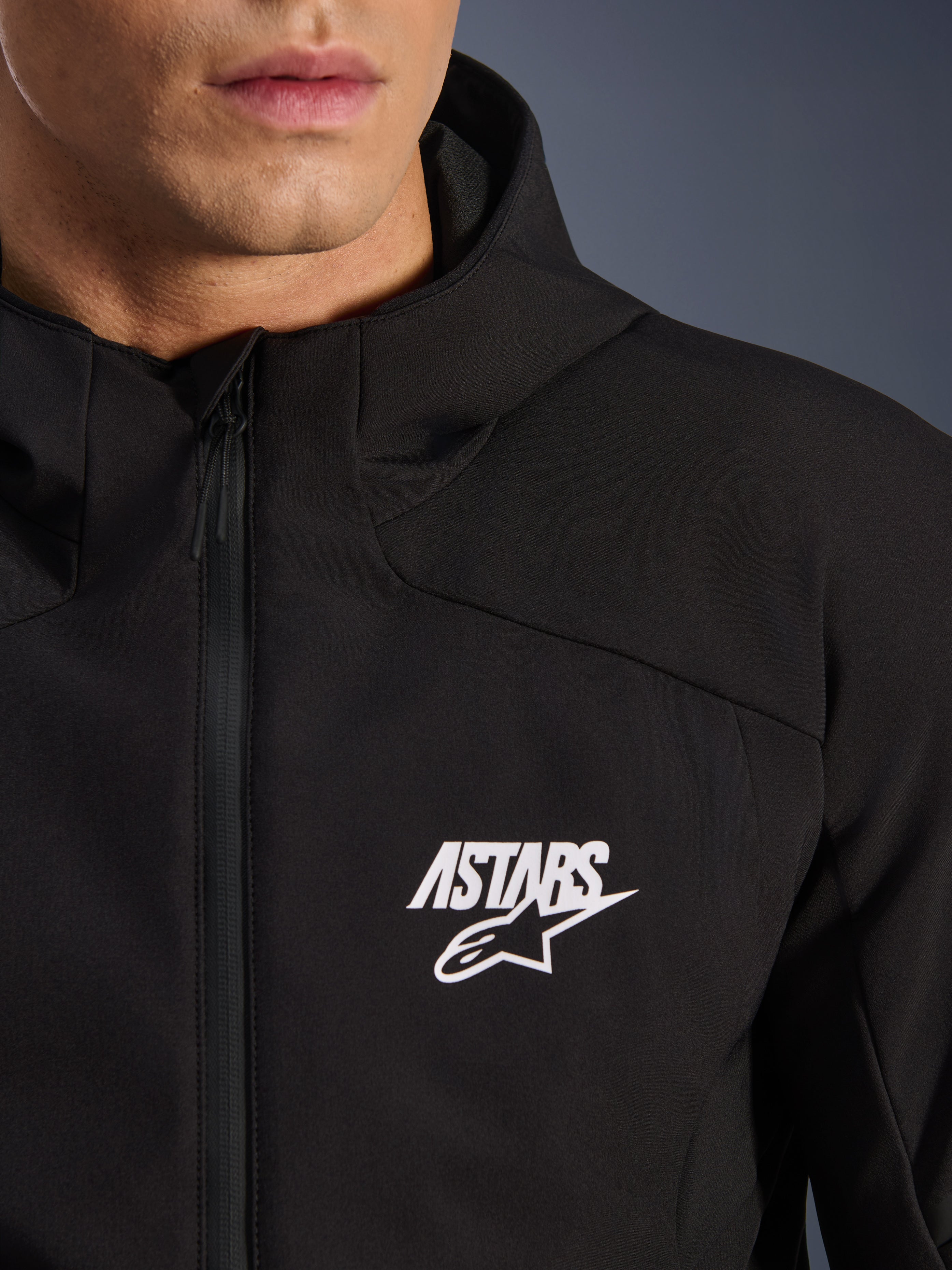 Alpinestars Aeroshell Wasserdichte Jacke, schwarze Herren Motorrad-Softshelljacke mit weißem ASTARS Stern-Logo, wasserdichtem Frontreißverschluss und integrierter Kapuze.