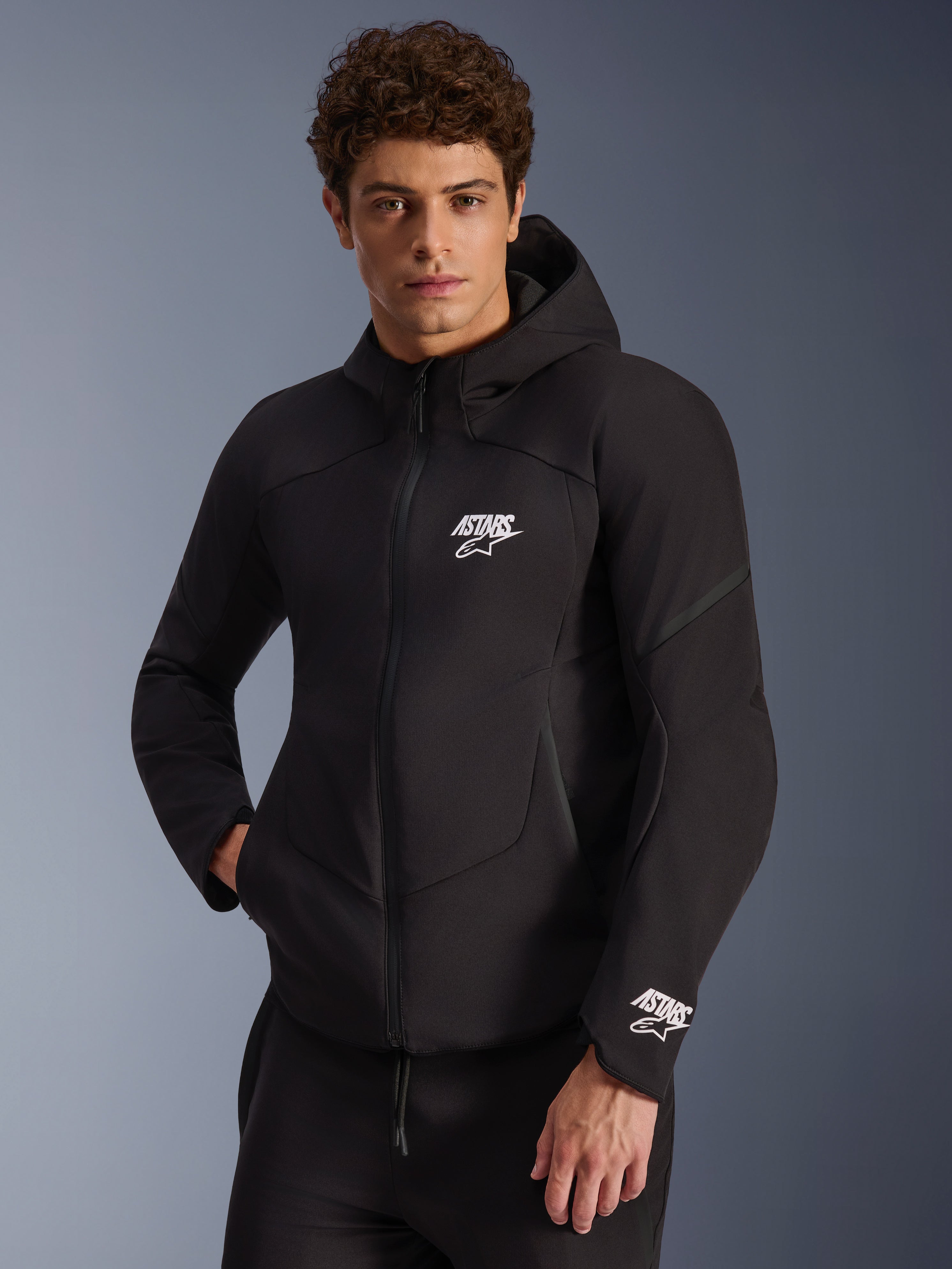 Alpinestars Aeroshell Wasserdichte Jacke, schwarze Herren-Softshell-Motorradjacke mit Kapuze und weißen Astars-Logos.