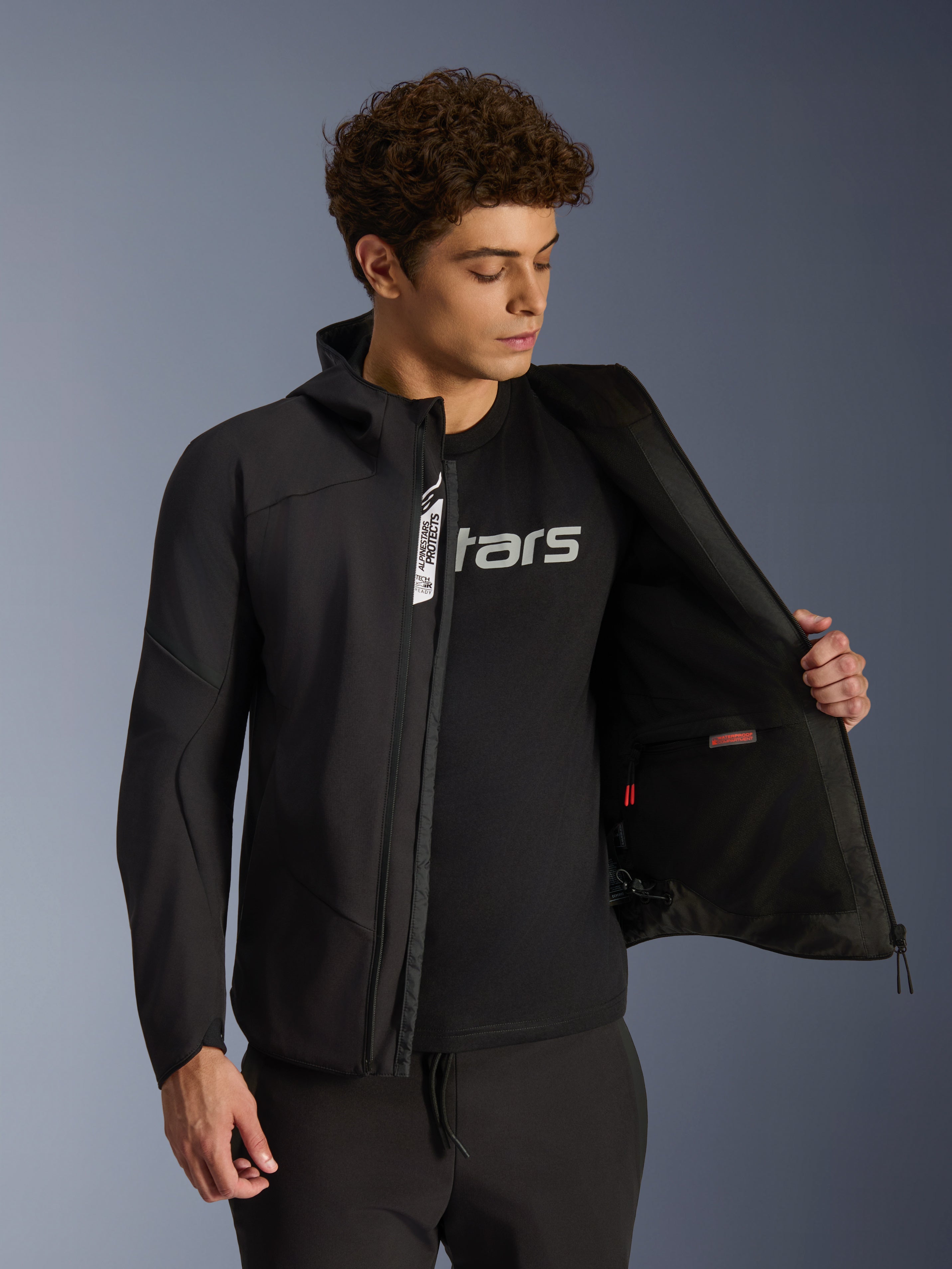 Alpinestars Aeroshell Wasserdichte Jacke, schwarze Urban-Softshell-Motorradjacke für Herren, geöffnet mit Innentasche.