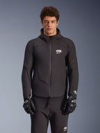 Alpinestars Aeroshell Wasserdichte Jacke, Urban-Motorradjacke für Herren, Schwarz, Textil-Softshell mit integrierter Kapuze, weißes Logo auf der Brust, getragen von einem Model mit schwarzen Handschuhen und Hose.