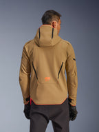 Alpinestars Aeroshell WP Jacke, wasserdichte Jacke, Dark Khaki und Orange Fluo, Rückansicht zeigt Hoodie-Design mit orangefarbenem Besatz an Kapuze und Saum, orangefarbenes Logo am unteren Rücken, getragen mit schwarzen Handschuhen, Crossover-Sport-Softshell-Motorradausrüstung