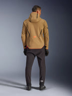 Alpinestars Aeroshell Waterproof Jacket in Dark Khaki Black Orange Fluo, Rückansicht eines Mannes, der die Softshell-Jacke mit Kapuze trägt, mit schwarzen Paspeln und orangefarbenem Logo, kombiniert mit schwarzer technischer Hose und Handschuhen.