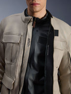 Alpinestars Borrego Drystar® Jacke in Warm Gray, Nahaufnahme der geöffneten Vorderseite, schwarzes Innenfutter und technischer Text im Inneren wie „ALPINESTARS PROTECTS“, Kompatibilität für Brustprotektoren, robuster Adventure-Motorrad-Stil.