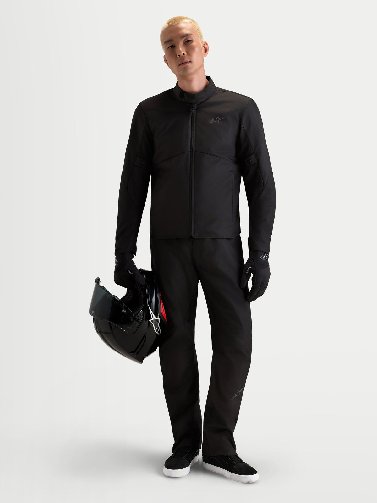 Alpinestars C-1 Waterproof Jacket, men's urban contemporary motorcycle textile jacket in black, front view on a model wearing matching pants, holding a helmet and wearing riding gloves.