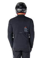Alpinestars AMT-8 Stretch Drystar® XF Jacke, Rückansicht, Schwarz, getragen mit schwarzem Helm und Hose, mit Alpinestars Motion Technology Branding auf dem Rücken, Adventure-Touring-Design aus ergonomischem Stretchmaterial.