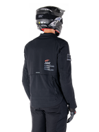 Rückansicht eines Fahrers in der Alpinestars AMT-8 Stretch Drystar® XF Jacke in Schwarz, mit 'AMT Alpinestars Motion Technology' Branding auf dem Rücken, technischen Belüftungsreißverschlüssen, kombiniert mit einem schwarzen Motorradhelm und Handschuhen