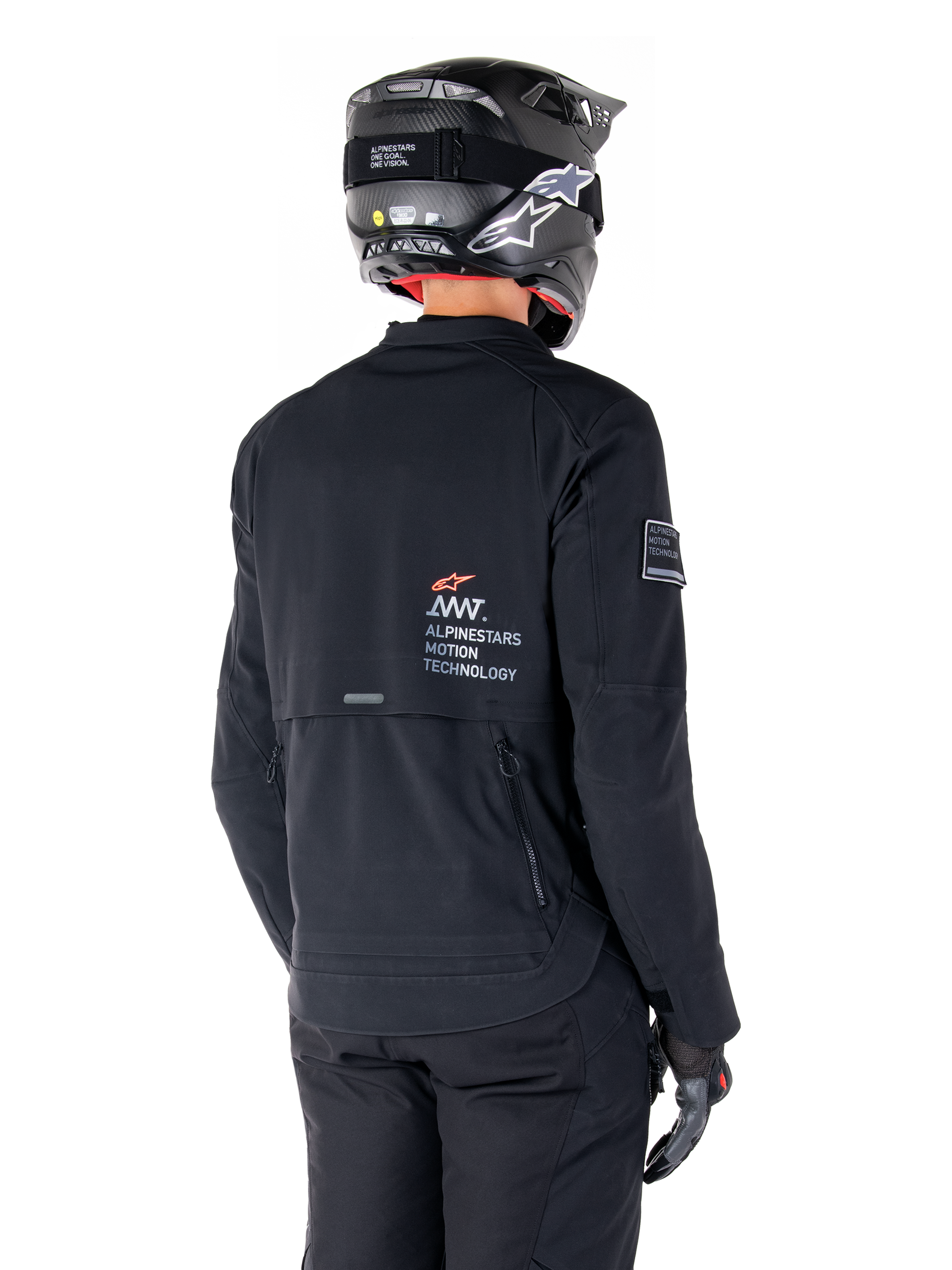 Rückansicht eines Fahrers in der Alpinestars AMT-8 Stretch Drystar® XF Jacke in Schwarz, mit 'AMT Alpinestars Motion Technology' Branding auf dem Rücken, technischen Belüftungsreißverschlüssen, kombiniert mit einem schwarzen Motorradhelm und Handschuhen