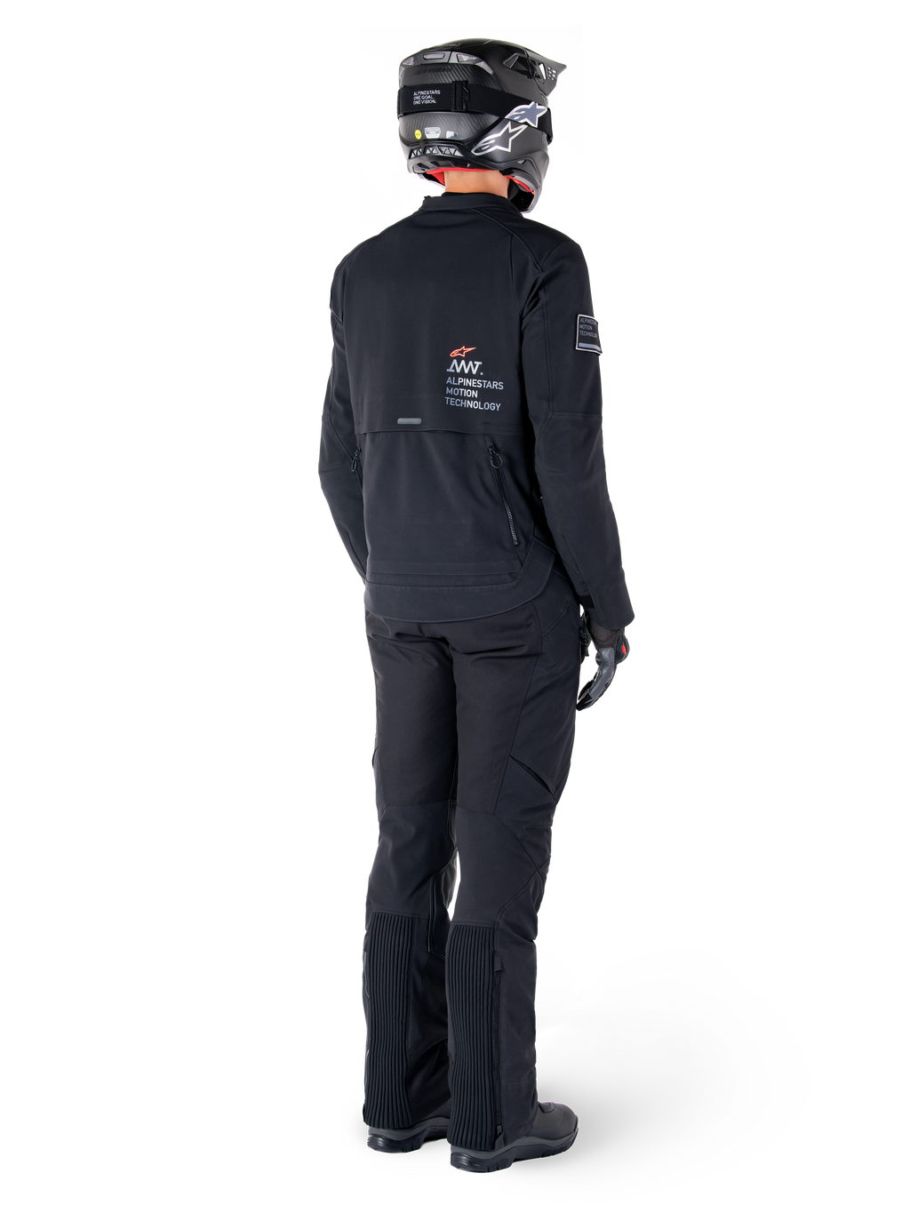 Alpinestars AMT-8 Stretch Drystar® XF Jacke, Schwarz, Rückansicht eines Fahrers mit passender schwarzer Hose und schwarzem Helm, mit „Alpinestars Motion Technology“-Branding auf dem Rücken, technisches Stretchmaterial für Adventure-Motorradtouren