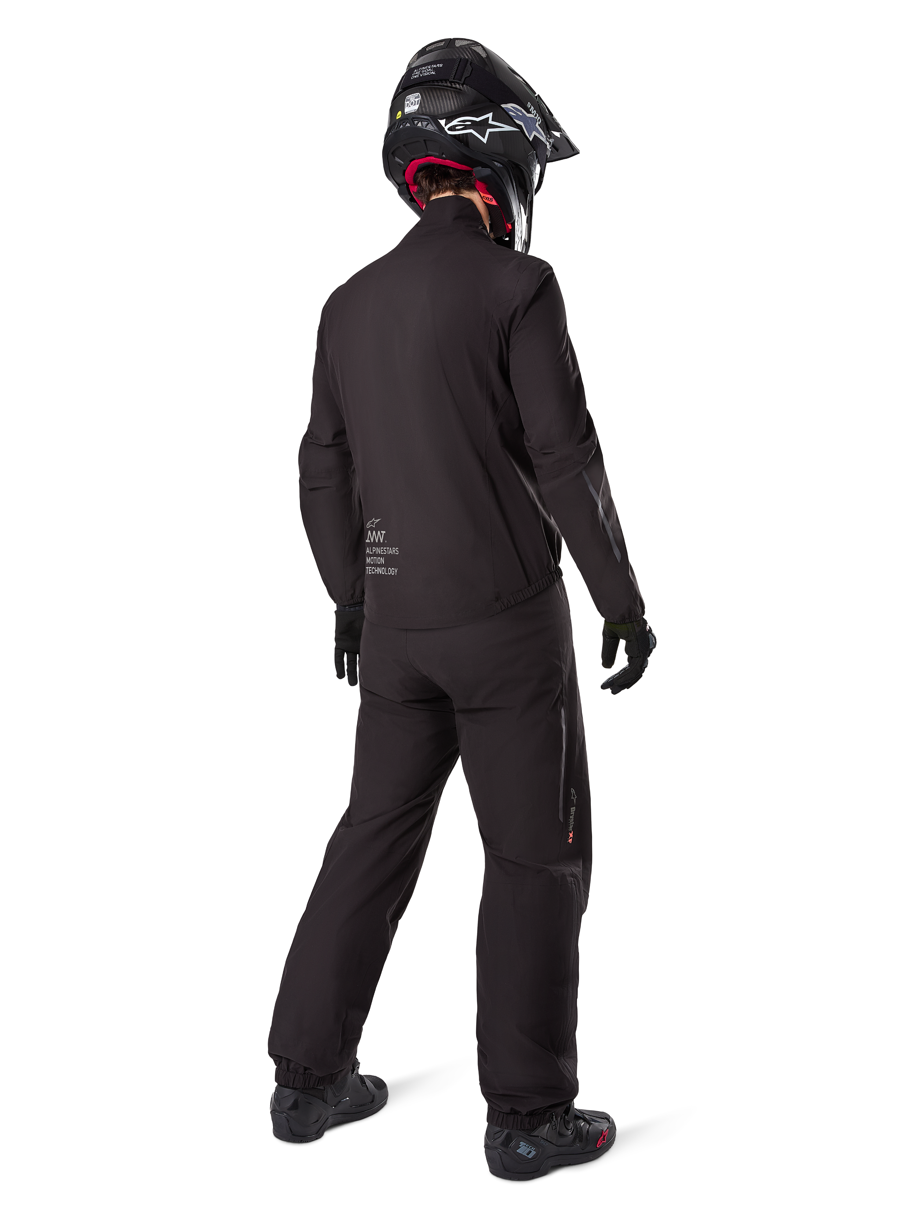 Rückansicht eines Fahrers mit dem Alpinestars AMT-8 Stretch Drystar® XF Jackenfutter, schwarze technische Motorradausrüstung, getragen mit passender Hose und schwarzem Helm, mit „AMT Alpinestars Motion Technology“-Branding auf dem Rücken, schlichtes minimalistisches Design für Adventure-Touren