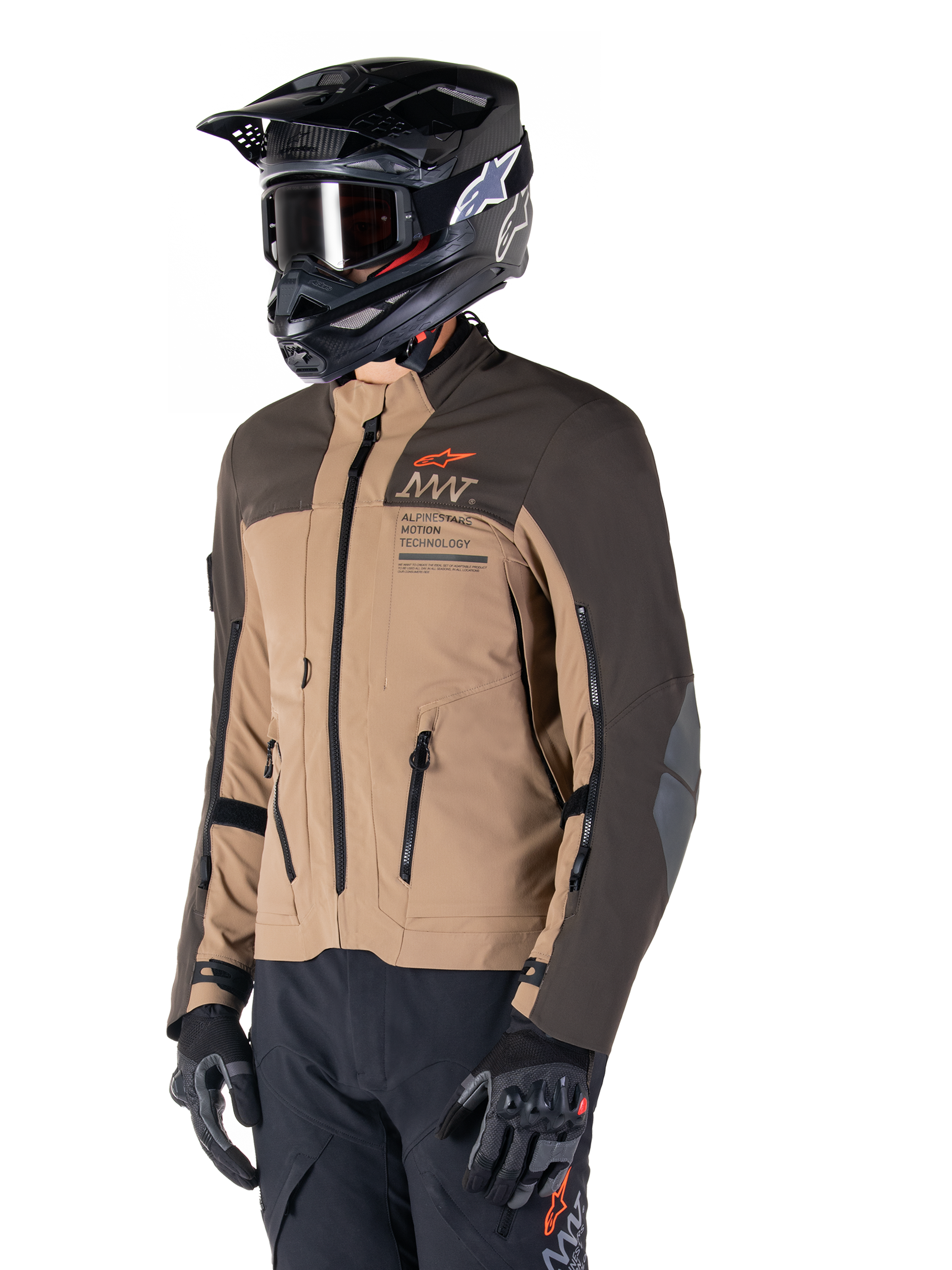 Alpinestars AMT-8 Stretch Drystar® XF Jacke, Adventure-Motorradjacke, Dunkelbraun und Dunkles Khaki, getragen mit einem schwarzen Offroad-Helm und Goggles, mit Alpinestars Motion Technology Branding und Belüftungsöffnungen mit Reißverschluss.