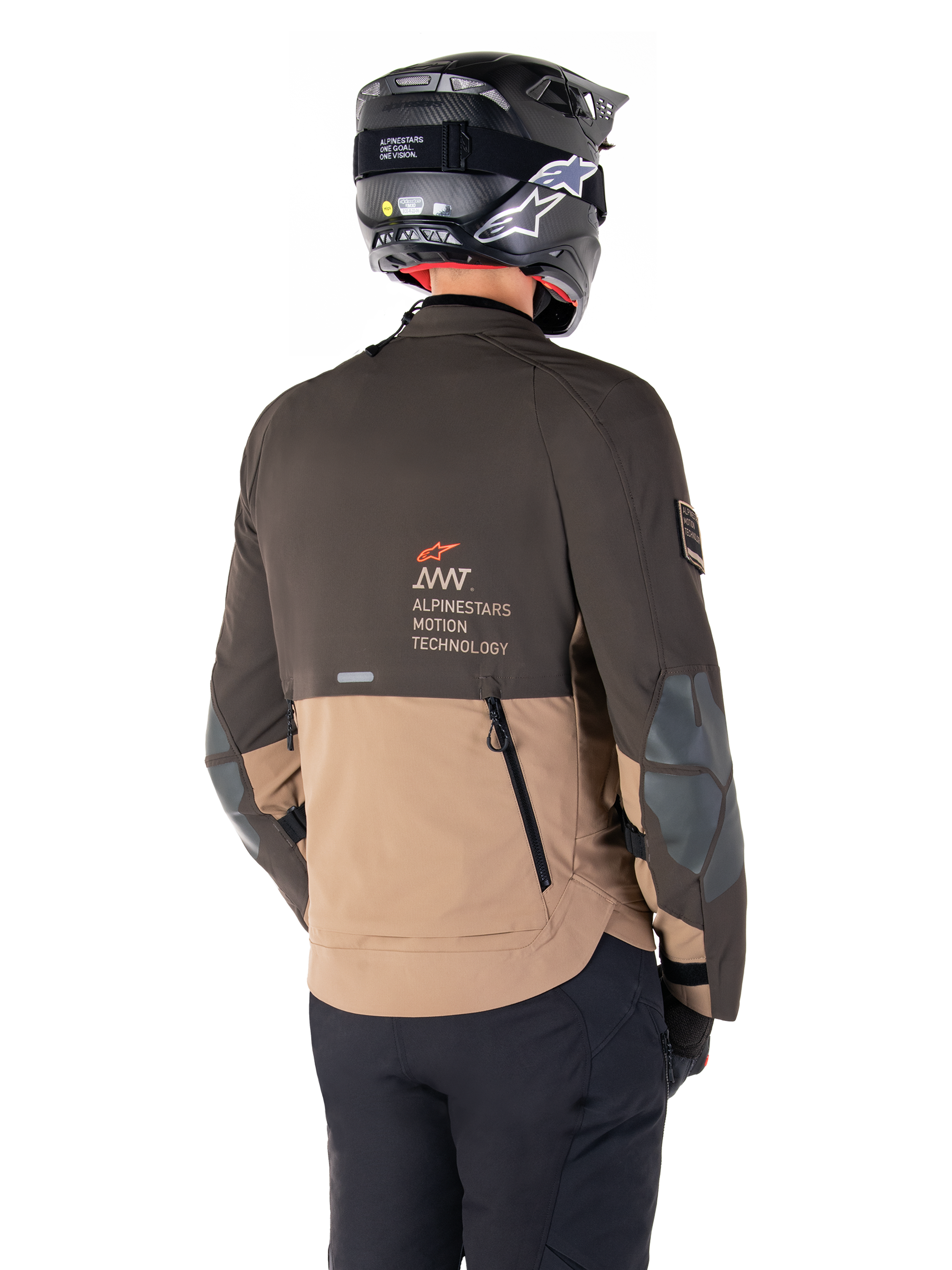Alpinestars AMT-8 Stretch Drystar® XF Jacke, Adventure-Motorradjacke, Dunkelbraun und Dunkles Khaki, Rückansicht mit AMT Alpinestars Motion Technology Branding, zweifarbiges Textildesign mit Belüftungsreißverschlüssen am Rücken und Luftauslass im Schindel-Design, getragen mit schwarzem Helm und Motorradhose