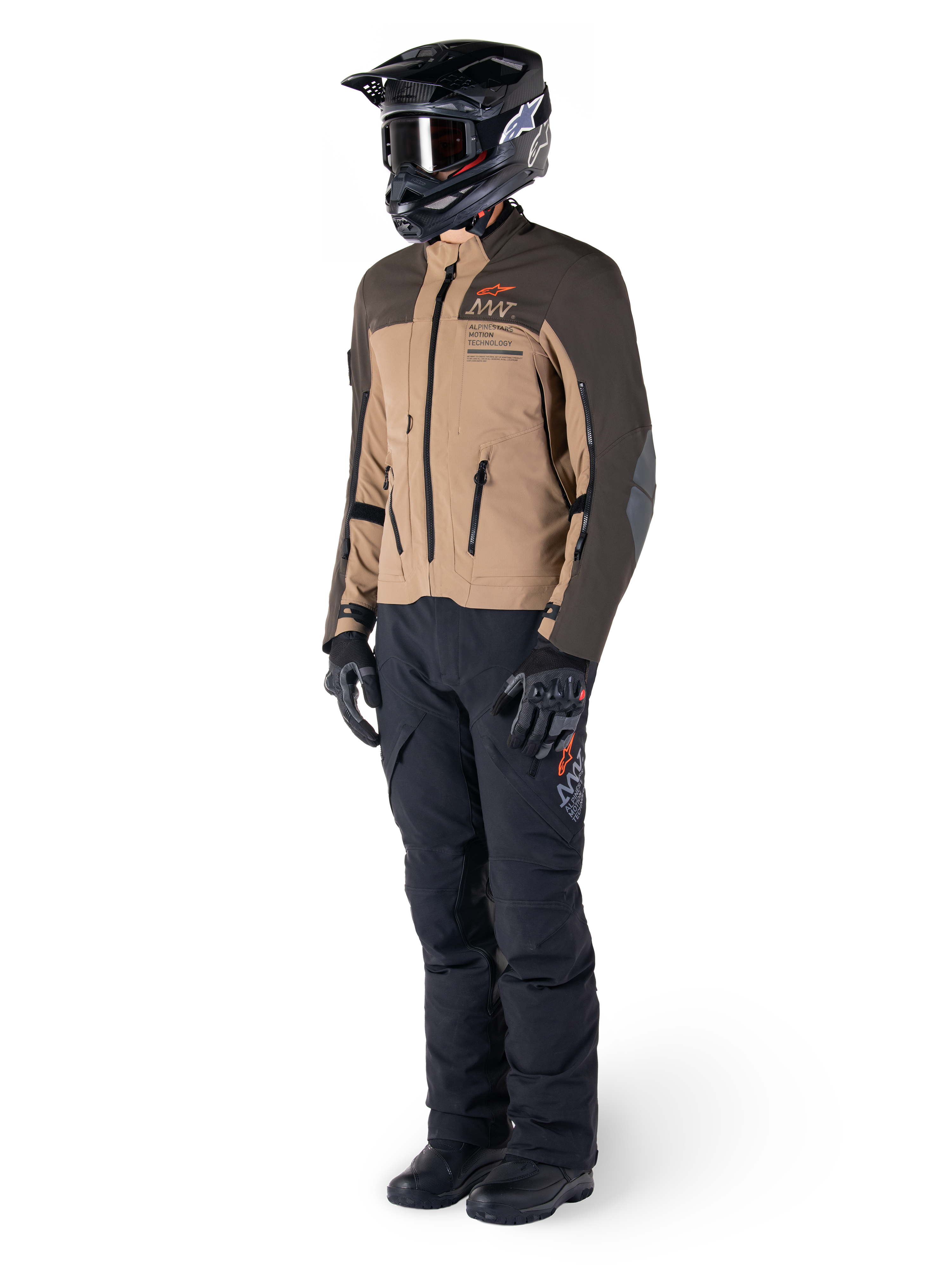Adventure-Fahrer in kompletter Ausrüstung, Alpinestars AMT-8 Stretch Drystar® XF Jacke in Dunkelbraun und Dunkelkhaki, kombiniert mit schwarzer Adventure-Hose, schwarzem Helm, Handschuhen und Stiefeln, mit orangefarbenem AMT-Branding und technischen Belüftungsreißverschlüssen für Langstreckentouren