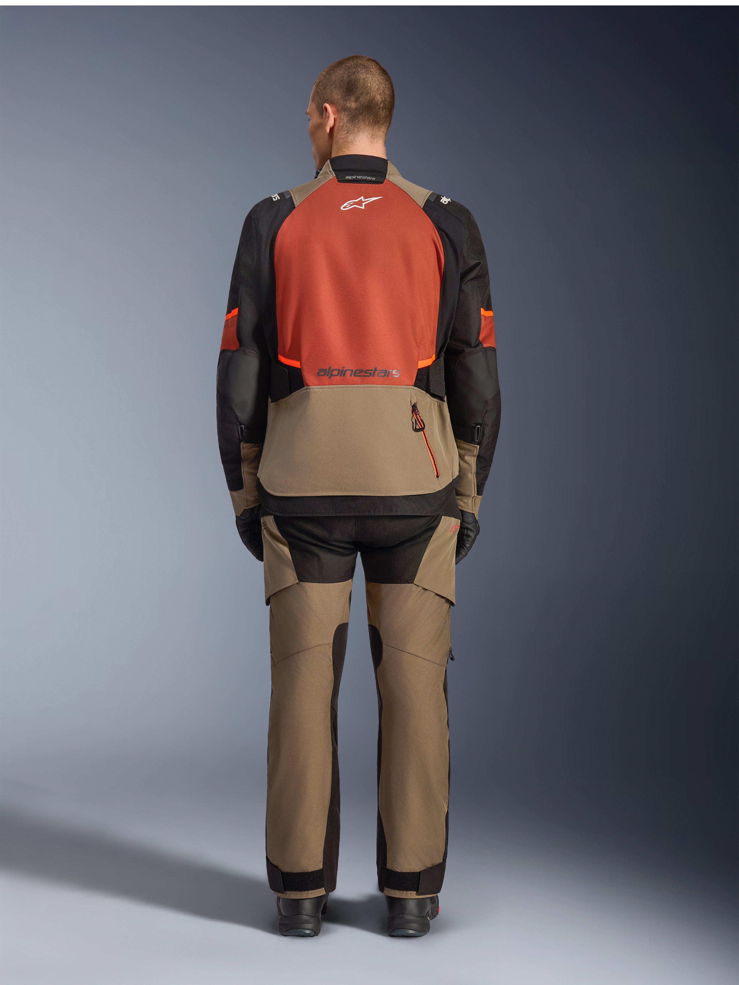 Alpinestars Andes V4 Drystar® Jacket, Walnut Rust Black, rear view of motorcycle touring jacket featuring rust-colored upper back panel and walnut lower section, worn with matching adventure pants and black boots