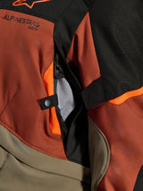Alpinestars Andes V4 Drystar® Jacket, Walnut Rust Black, close-up of direct ventilation vent with mesh lining, durable textile material with orange accents, snap button and Alpinestars logo detail