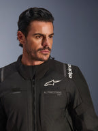 Alpinestars Andes V4 Drystar® Jacke, Schwarz, getragen von einem männlichen Model, Nahaufnahme von Brust und Schultern, mit weißen Alpinestars-Logos, Textilmaterial mit Belüftungsdetails und Trinkschlauch-Schlaufe, Adventure-Touring-Motorradausrüstung
