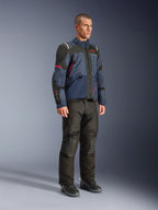 Männliches Modell trägt die Alpinestars Andes V4 Drystar® Jacke in Night Navy und Mood Indigo mit schwarzen Einsätzen und roten Akzenten, kombiniert mit einer schwarzen Motorradhose und Stiefeln, technische Adventure-Touring-Ausrüstung in einer Studioumgebung.