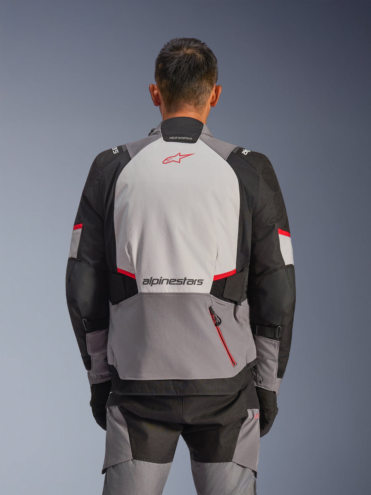 Alpinestars Andes V4 Drystar® Jacke, Rückansicht, Dunkelgrau, Eisgrau, Schwarz und Hellrot, mit rotem Astar-Logo und Alpinestars-Schriftzug auf der Rückseite, verstärkten Einsätzen und einer roten Reißverschlusstasche, Adventure-Motorradausrüstung