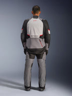 Alpinestars Andes V4 Drystar® Jacket, Adventure Motorcycle Jacket, Dark Gray Ice Gray Black and Bright Red, rear view of a rider wearing matching pants, featuring a large ice gray back panel with red logo, black reinforced shoulder sections, and adjustable waist straps for all-weather touring.