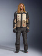 Alpinestars Andes V4 Drystar® Jacke, Walnut Mastic Black, getragen mit schwarzer Motorradhose und Handschuhen, im mehrteiligen Adventure-Design mit orangefarbenen Akzenten und Alpinestars-Branding, technische Textilausrüstung für Fahrten bei jedem Wetter