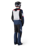 Rear view of a rider wearing the Alpinestars ST-1 Waterproof Jacket in Dark Blue Black Bright Red, paired with matching waterproof pants and a black helmet, featuring a prominent grey back panel with Alpinestars branding and an adventure touring design.