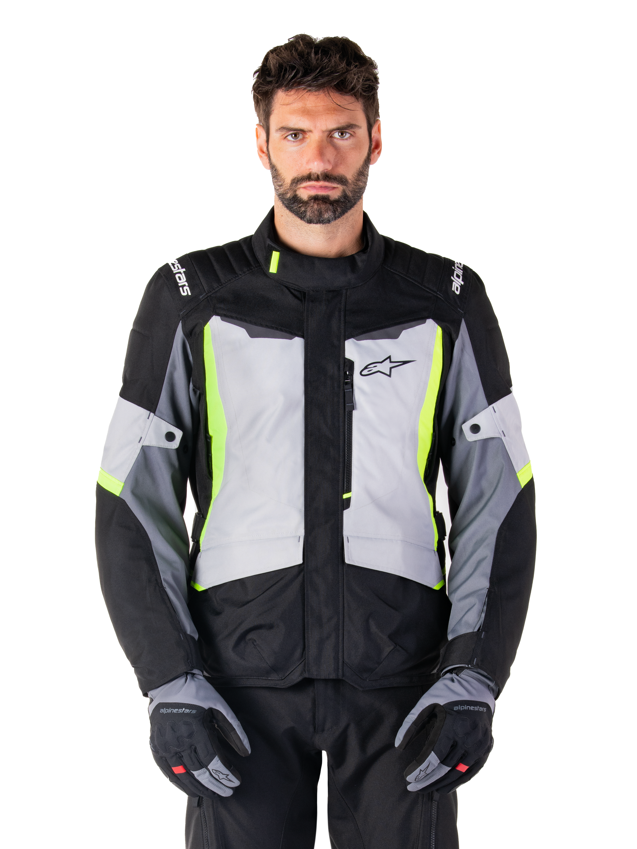 Alpinestars ST-1 Waterproof Jacke, Adventure-Touren-Motorradjacke, Ice Gray, Schwarz und Gelb Fluo, getragen von einem Mann mit passenden Handschuhen und schwarzer Hose, mit neongelben Akzenten auf der Brust und am Kragen, Alpinestars-Logo auf der Brust