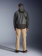 Alpinestars Mospher Waterproof Jacke, schwarzer Motorrad-Parka in der Rückansicht, mit MO.ST.EQ-Logo auf dem oberen Rücken und Ripstop-Gewebe-Konstruktion, getragen mit hellbrauner Cargohose und schwarzen Sneakern, urbaner Pendler-Stil.