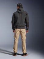 Alpinestars Moblast Wasserdichte Jacke, Schwarz, Rückansicht eines urbanen Motorrad-Hoodies, getragen mit beigen Cargohosen und schwarzen Sneakern, minimalistisches Design mit vertikalem „astars“-Branding am oberen Rücken, moderne Allwetter-Fahrausrüstung
