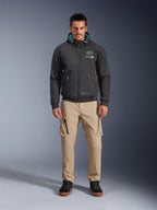 Alpinestars Moblast wasserdichte Jacke, schwarzer urbaner Motorrad-Hoodie mit teal-farbenem Kapuzeninnenfutter, getragen mit sandfarbenen Cargo-Hosen und schwarzen High-Top-Stiefeln, moderne Ganzjahres-Fahrausrüstung
