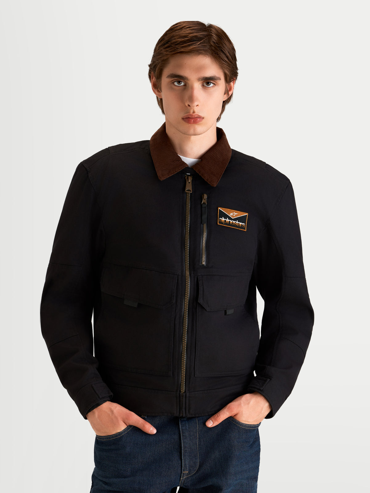 Alpinestars Mustang Waterproof Jacket, men's urban motorcycle textile jacket in dark anthracite and dark brown, front view on a model wearing workwear-styled riding apparel with a contrasting corduroy collar.