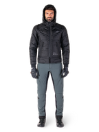 Alpinestars Mohobbs Waterproof Jacket in black, male model wearing quilted padded bomber jacket with hood, paired with grey riding pants, black gloves, and black boots, urban contemporary motorcycle gear.