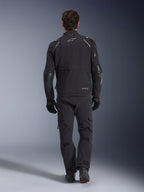 Alpinestars Andes Pro Drystar® XF Jacke, Adventure-Tourenjacke, Schwarz und Dunkelgrau, Rückansicht mit großer Cargotasche und verstärkten Ellbogen-Einsätzen, getragen mit passender schwarzer Hose und Handschuhen, elegantes funktionelles Design für Fahrten bei jedem Wetter