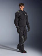 Alpinestars Andes Pro Drystar® XF Jacke, Motorradjacke in Schwarz und Dunkelgrau, getragen von männlichem Model mit passender Adventure-Hose, Handschuhen und Stiefeln, Ganzkörper-Studioaufnahme, technische Adventure-Touring-Ausrüstung mit reflektierenden Details und Branding