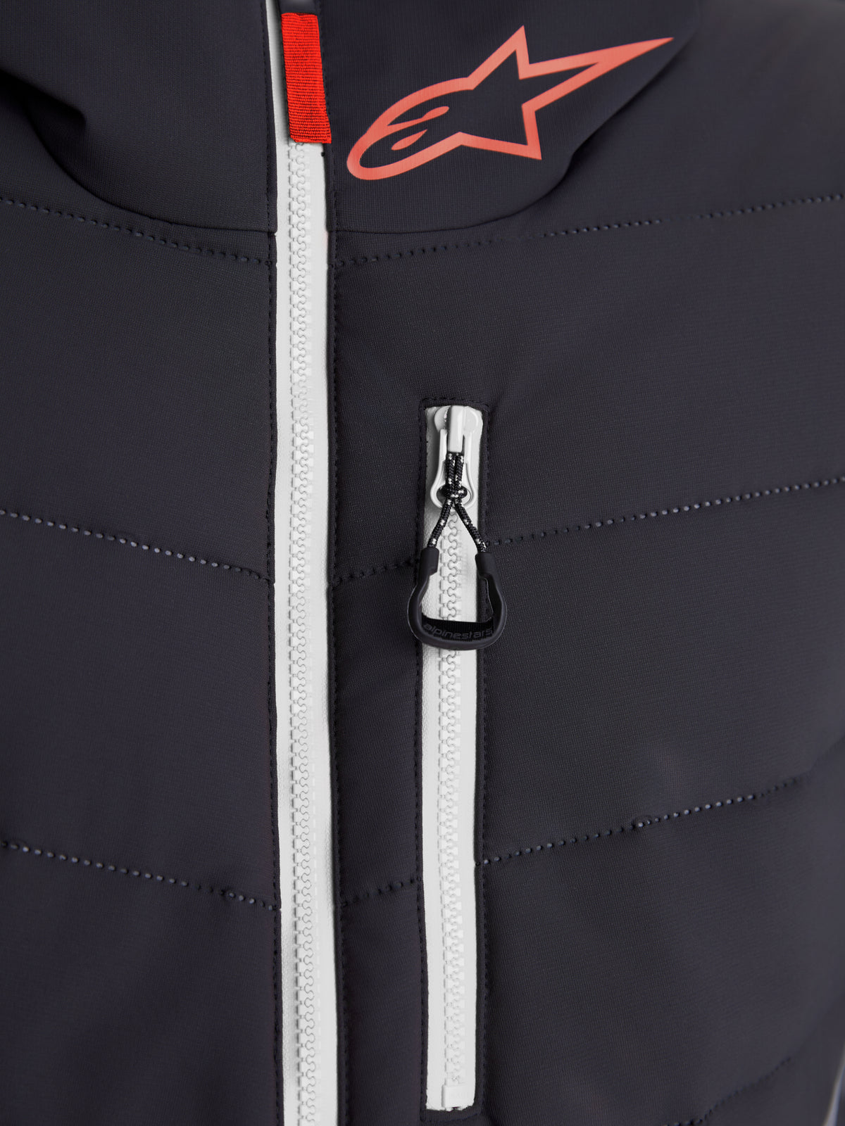 Alpinestars Therma-Tech Wasserdicht Jacke, urbane Motorradjacke, Nahaufnahme der verschweißten Steppkonstruktion mit weißem wasserdichtem Hauptreißverschluss und Alpinestars-Logo, Schwarz und Dunkelgrau mit roten Akzenten