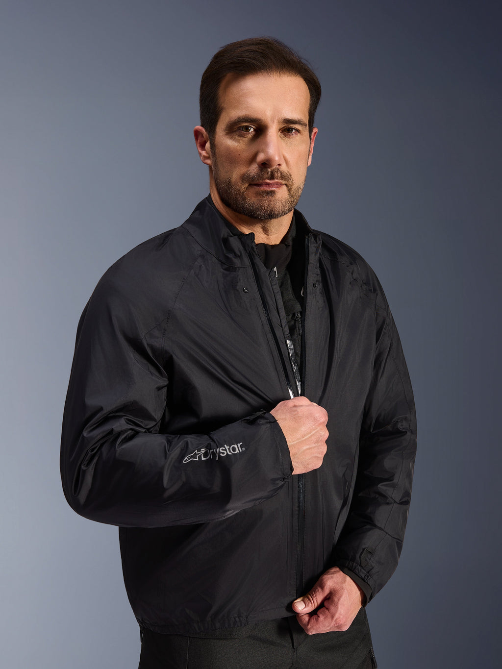 Alpinestars Cusco Drystar® Jacke, schwarze wasserfeste Membranschicht, getragen von einem männlichen Model, mit Drystar-Logo auf dem Ärmel, leichte Adventure-Touring-Motorradausrüstung