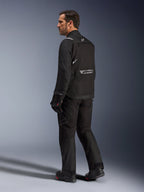 Alpinestars Cusco Drystar® Jacke, schwarze Motorradjacke, Rückansicht eines männlichen Models in kompletter Fahrausrüstung, reflektierendes Branding auf dem Rücken, Textilkonstruktion mit technischen Einsätzen, abgestimmtes Outfit für Road-Adventure-Touren