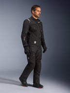 Männliches Model in der Alpinestars Cusco Drystar® Jacke in Schwarz, Adventure-Touring-Motorradausrüstung mit passender schwarzer Hose und Stiefeln, Multi-Pocket-Design, „Drystar“-Branding am Ärmel und „Terra“-Logo-Patch.