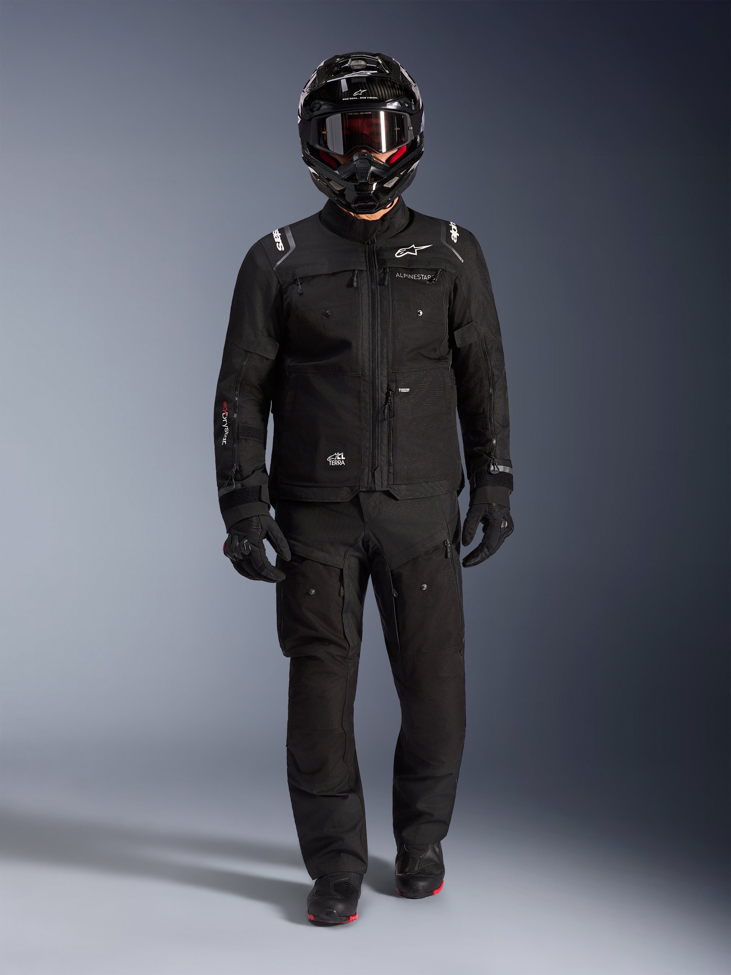 Alpinestars Cusco Drystar® Jacke, schwarze Adventure-Motorrad-Tourenjacke, getragen mit passender schwarzer Hose, Integralhelm, Handschuhen und Stiefeln, mit technischer Ripstop-Konstruktion und weißem Alpinestars-Branding